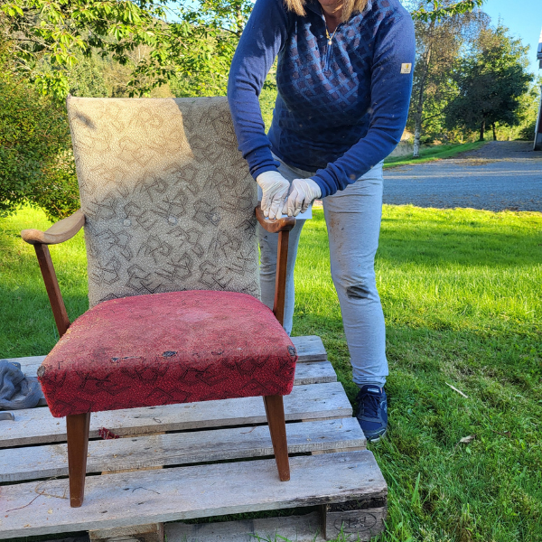 Gammel retro stol og person som fjerner lakk på treverket